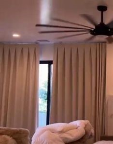Custom motorized blackout curtains fully closed on a large master bedroom window in Tustin, providing total privacy and light blocking.